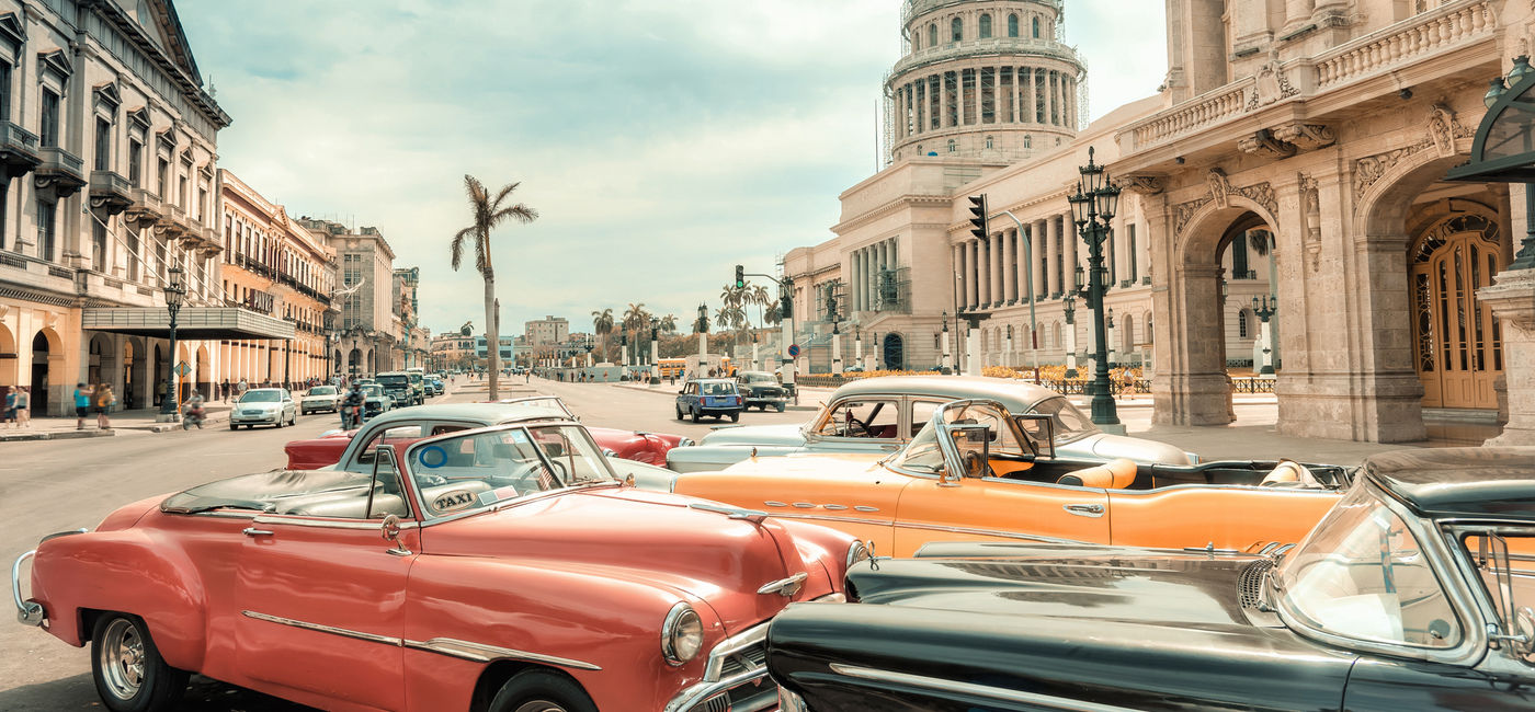 Image: Classic cars parked in front of the Capitol in Havana, Cuba. (photo via iStock/Getty E+/golero)
