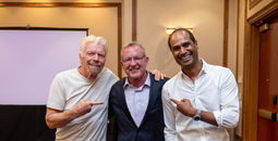 John Lovell (center) poses with Virgin Voyages founder Richard Branson (left) and CEO Nirmal Saverimuttu (right)