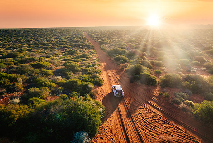 Driving through the Australian outback at sunset.