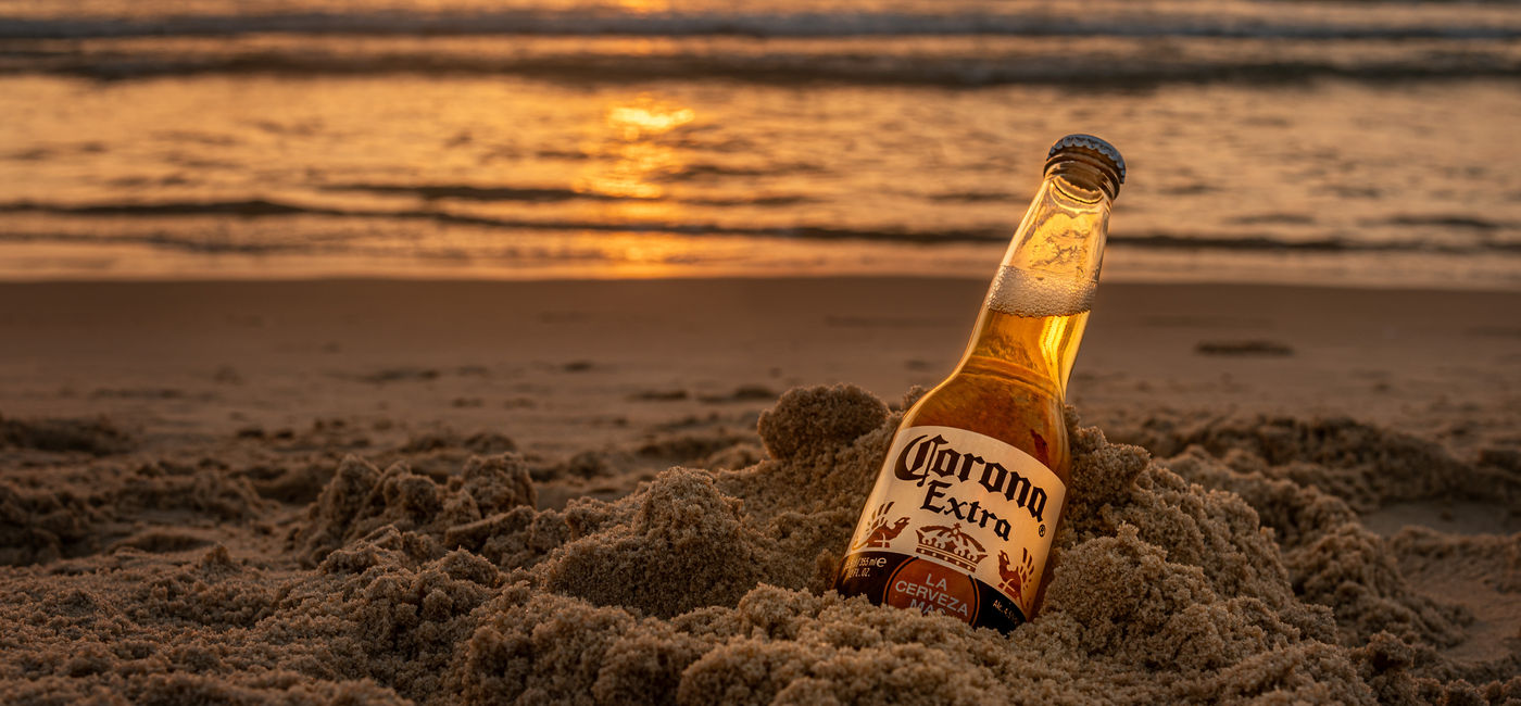 Image: Bottle of Corona on a beach. (Photo Credit: Mariia/Adobe)