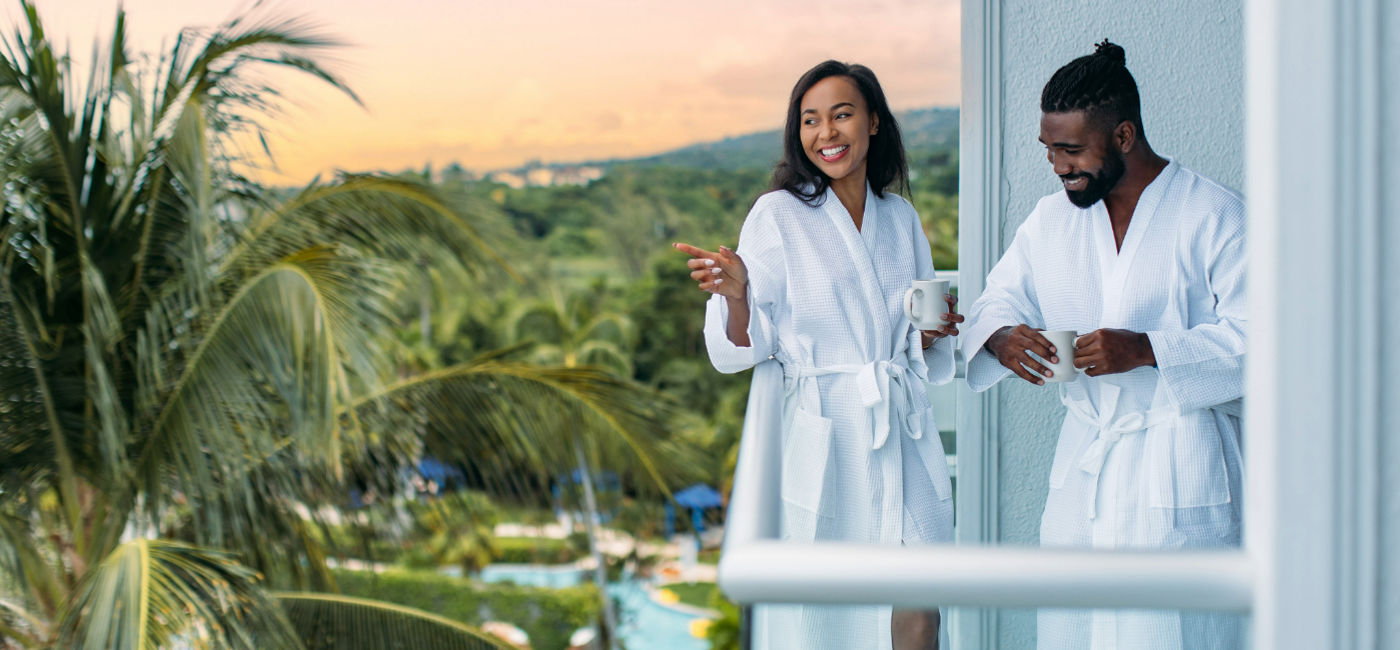 Image: A couple enjoys their balcony at the Hilton Rose Hall in Jamaica. (Photo Credit: Playa Hotels & Resorts)