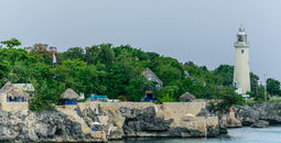 The Negril Lighthouse beside a cliffside hotel resort on the coast of Negril, Jamaica.
