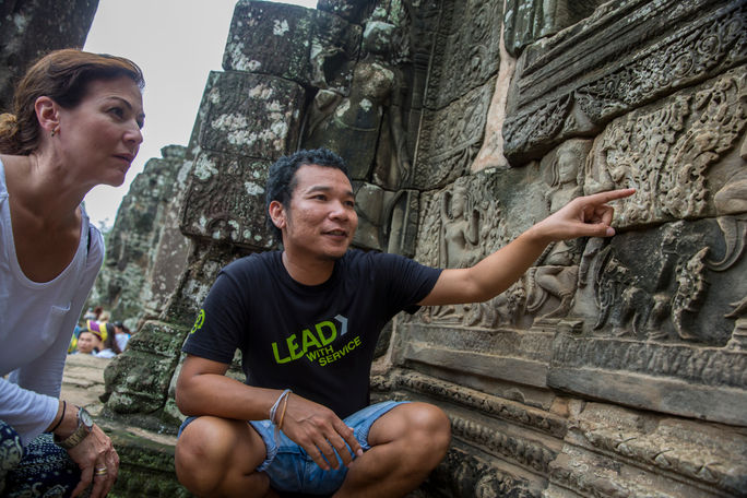A G Adventures CEO explains carvings to a traveler at Angkor Wat. G Adventures, Angkor wat tours, angkor wat