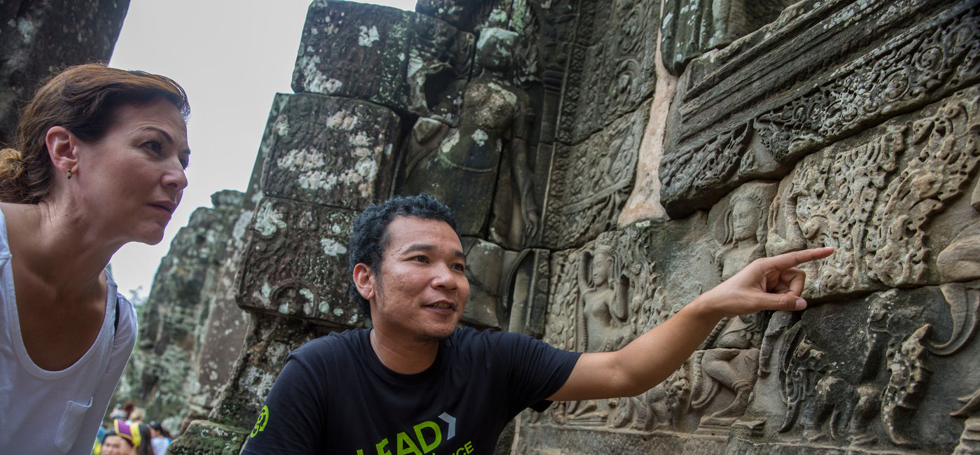 Image: Un guide de G Adventures commente les bas-reliefs d’Angkor Wat pour un voyageur (Source: G Adventures)