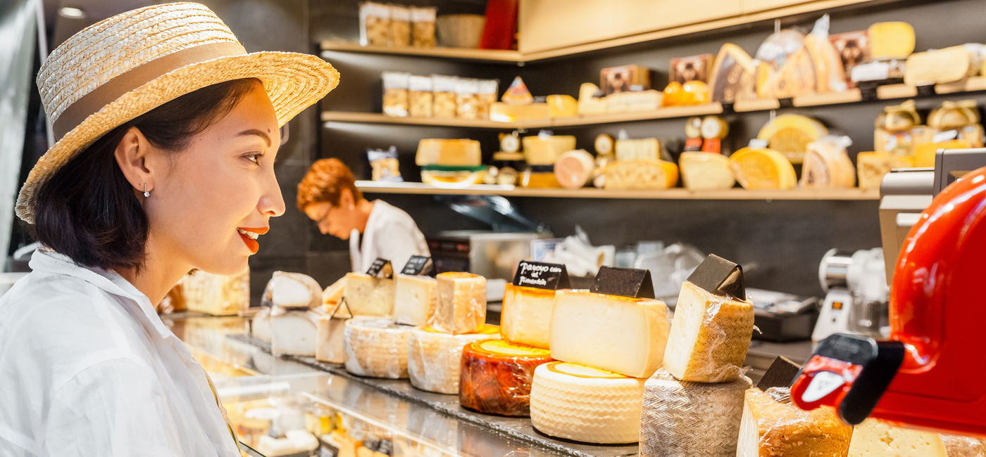 Image: A woman peruses a fromagerie in France. 