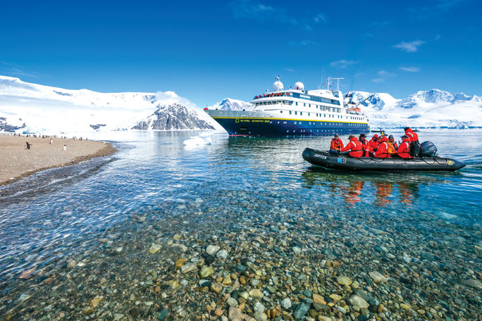 Lindblad Expeditions A zodiac cruises in front of a Lindblad Expeditions vessel.
