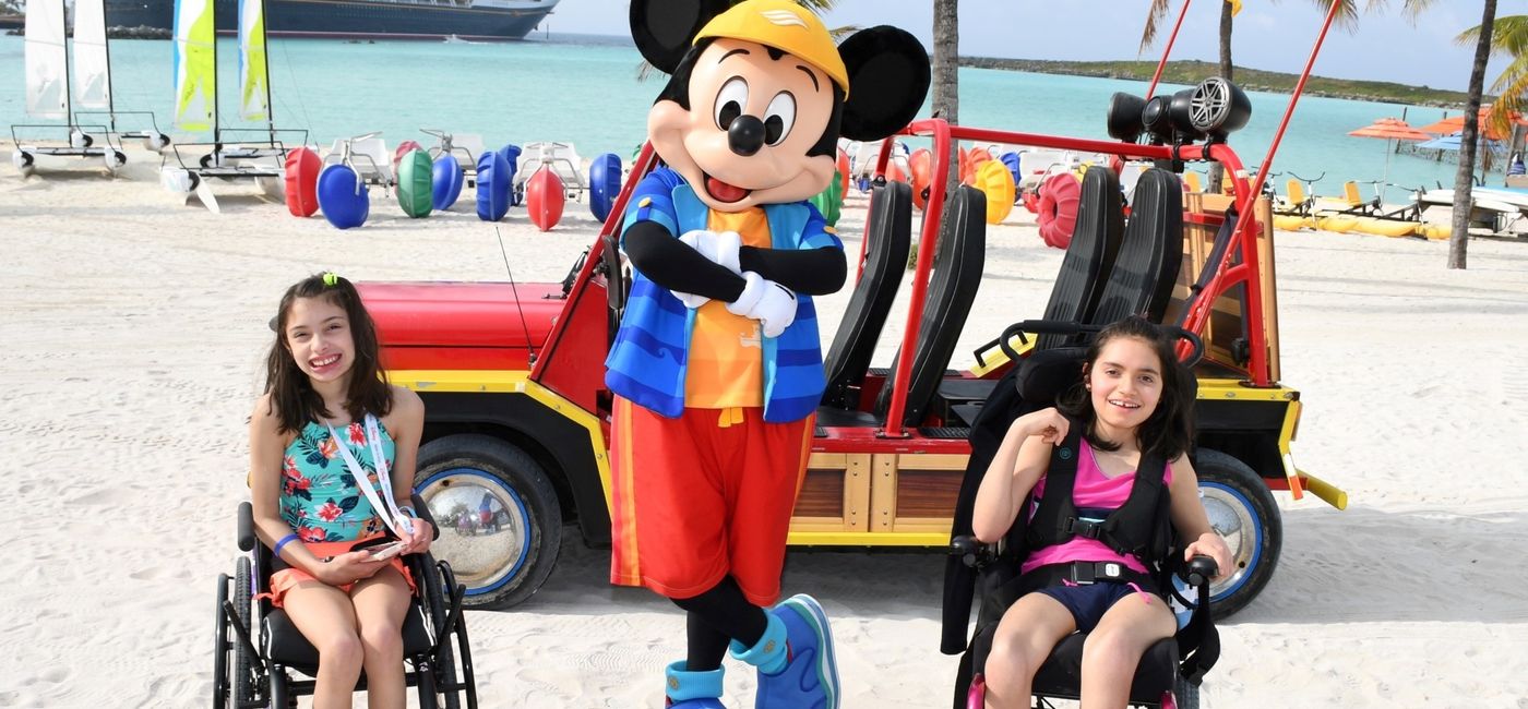 Image: Kara and Ella Betancourt pose with Mickey Mouse at Disney Castaway Cay. (Photo Credit: Disney Cruise Line)