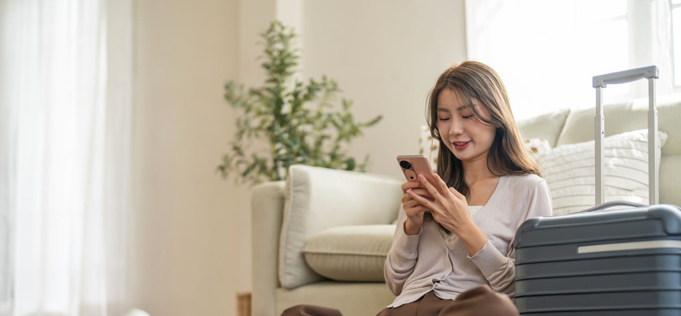 Image: Woman booking travel from her smartphone. (Photo Credit: Adobe/Art_Photo)