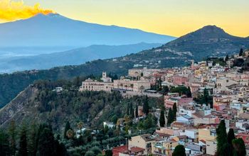 The town of Taormina in Sicily, Italy, with Mount Etna visible in the distance.