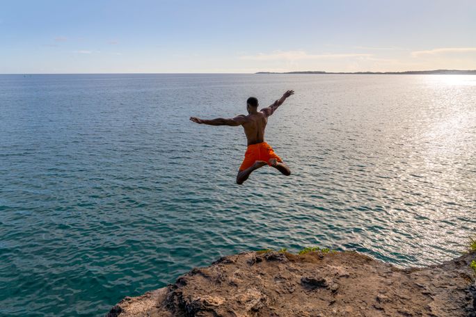 A man jumps off a cliff into the sea in Bermuda. Bermuda, Bermuda Tourism Authority, traveler, experiential travel