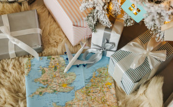 Toy airplane sitting on a map surrounded by holiday gifts.