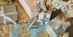 Toy airplane sitting on a map surrounded by holiday gifts.