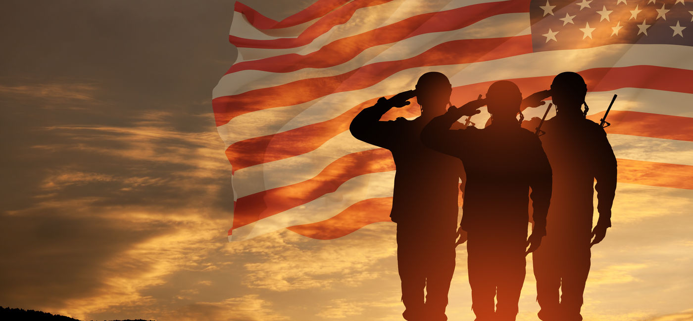 Image: US Army soldiers saluting with an American flag in the background. (Photo Credit: Adobe Stock/hamara)