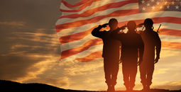 US Army soldiers saluting with an American flag in the background.