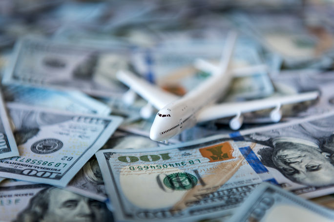 A toy airplane sitting atop a pile of US cash. A toy airplane sitting atop a pile of US cash.