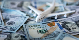 A toy airplane sitting atop a pile of US cash.