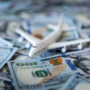 A toy airplane sitting atop a pile of US cash.