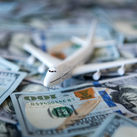 A toy airplane sitting atop a pile of US cash.