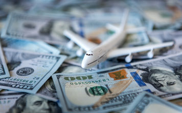 A toy airplane sitting atop a pile of US cash.