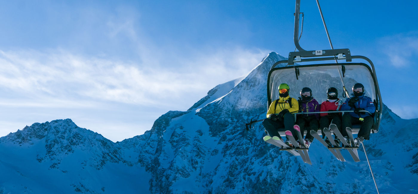 Image: Skiers on a chairlift (Photo Credit: DarwelShots/Adobe Stock)