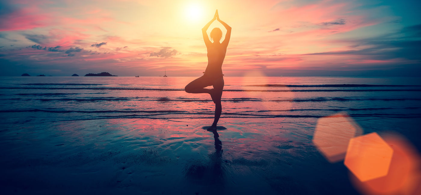 Image: Woman doing yoga on the beach at sunset.  (Photo Credit: Adobe Stock/De Visu)