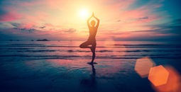 Woman doing yoga on the beach at sunset.