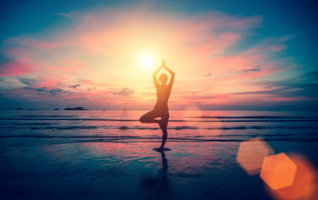 Woman doing yoga on the beach at sunset. 
