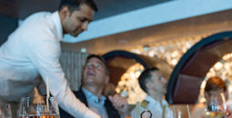 A waiter serves guests at Fine Cut Steakhouse aboard Celebrity Beyond.
