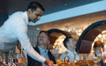 A waiter serves guests at Fine Cut Steakhouse aboard Celebrity Beyond.