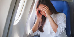 Woman flying on a plane while dealing with headache pain.
