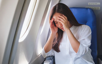 Woman flying on a plane while dealing with headache pain.