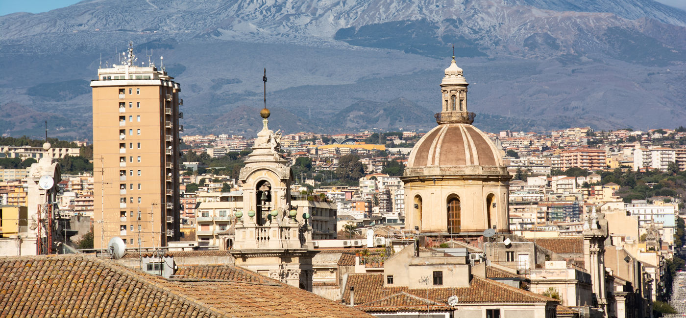 Image: The city of Catania under scenic Mount Etna in Sicily. (Photo Credit: Rosario Scalia / Adobe Stock)