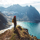 Backpacker standing on top of a mountain overlooking the sea.