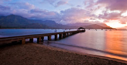 Pier into ocean with sunset behind