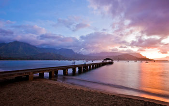 Pier into ocean with sunset behind