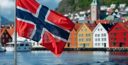 Norwegian national flag in front of colorful houses in Bergen, Norway.