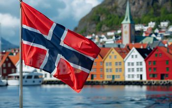 Norwegian national flag in front of colorful houses in Bergen, Norway.