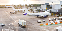 Airport tarmac with airplanes and service vehicles at sunset.