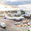 Airport tarmac with airplanes and service vehicles at sunset.