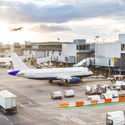 Airport tarmac with airplanes and service vehicles at sunset.