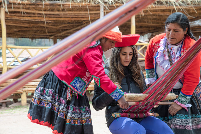 Two women of Peru's Sacred Valley Ccaccaccollo Women’s Weaving Co-op teach a traveler their techniques. Peru, peru tours, Sacred Valley, G Adventures