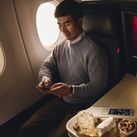 Flier in Delta One cabin with cocktail and snack