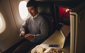 Flier in Delta One cabin with cocktail and snack