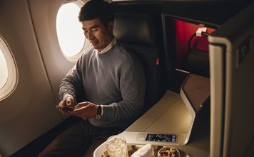 Flier in Delta One cabin with cocktail and snack