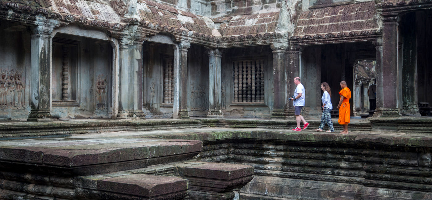 Image: Travelers walk through Angkor Wat in Cambodia with a monk. (Photo Credit: G Adventures)