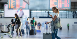 Woman walking into an airport on her smartphone