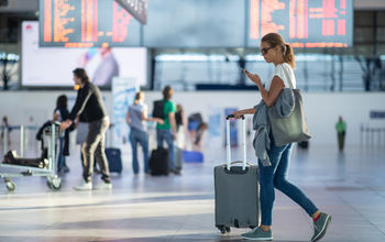 Woman walking into an airport on her smartphone