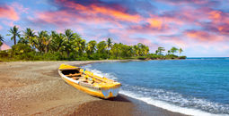 Wooden fishing boat on beach at sunset in Jamaica.