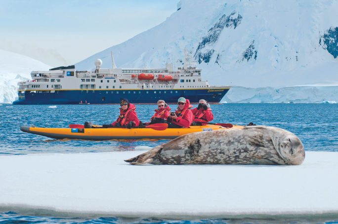 Travelers in a kayak photograph a sleeping seal during a Lindblad Expeditions-National Geographic expedition cruise in Antarctica. Lindblad Expeditions-National Geographic, seals, animals, expedition cruise, Antarctica, antarctica cruise