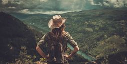 Female hiker enjoying valley landscapes from the top of a mountain.